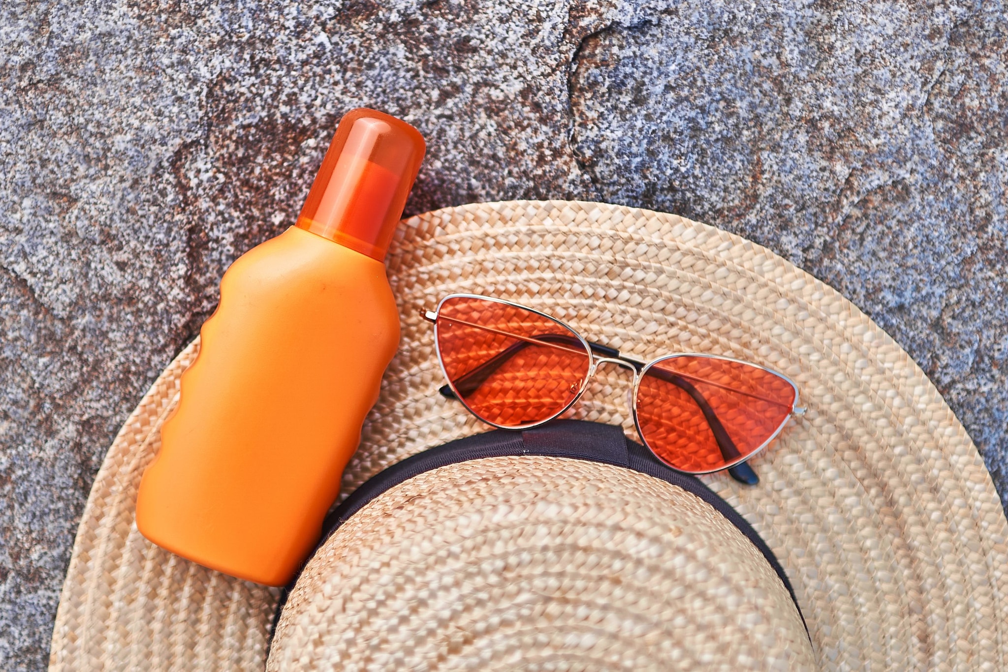 Wide-brim hat, sun glasses, and sunscreen bottle.