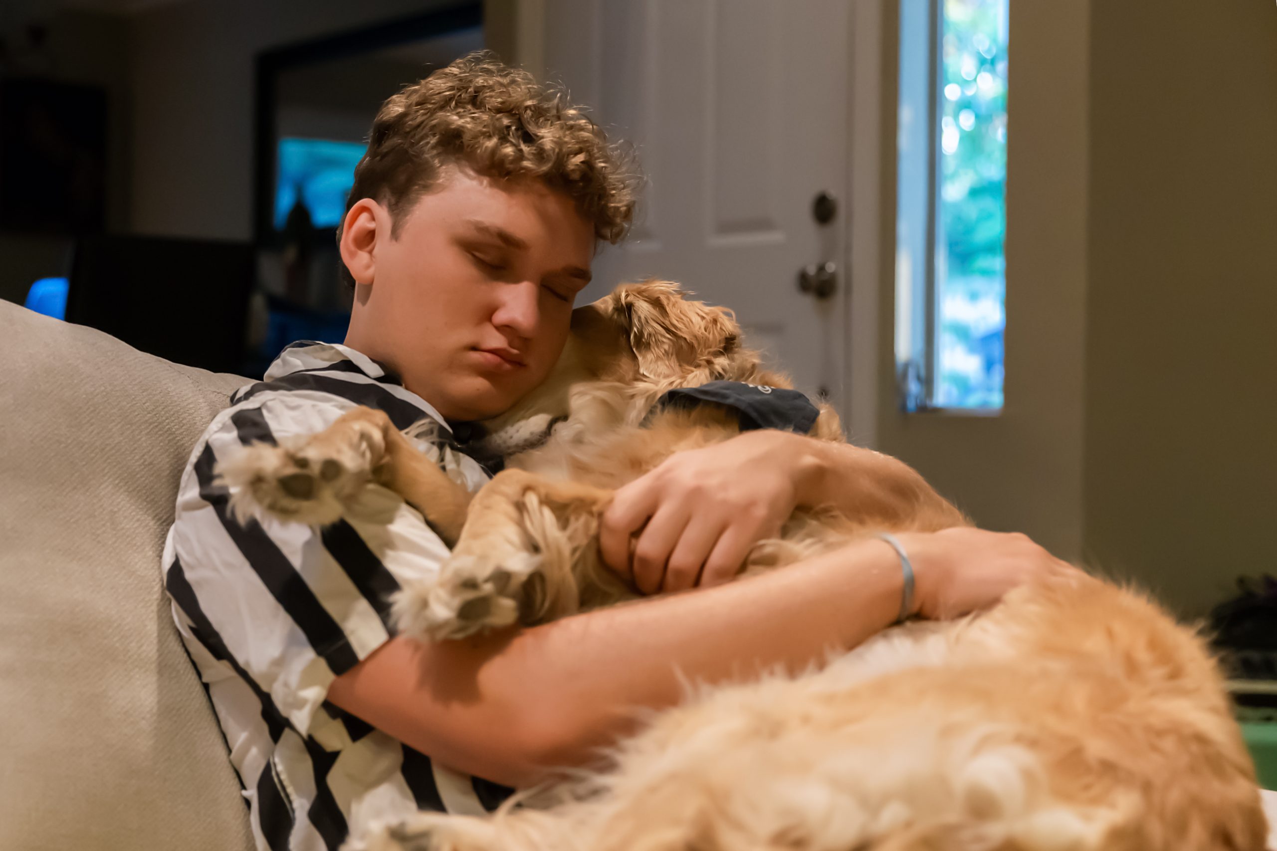 Teenage boy cuddling with golden retriever